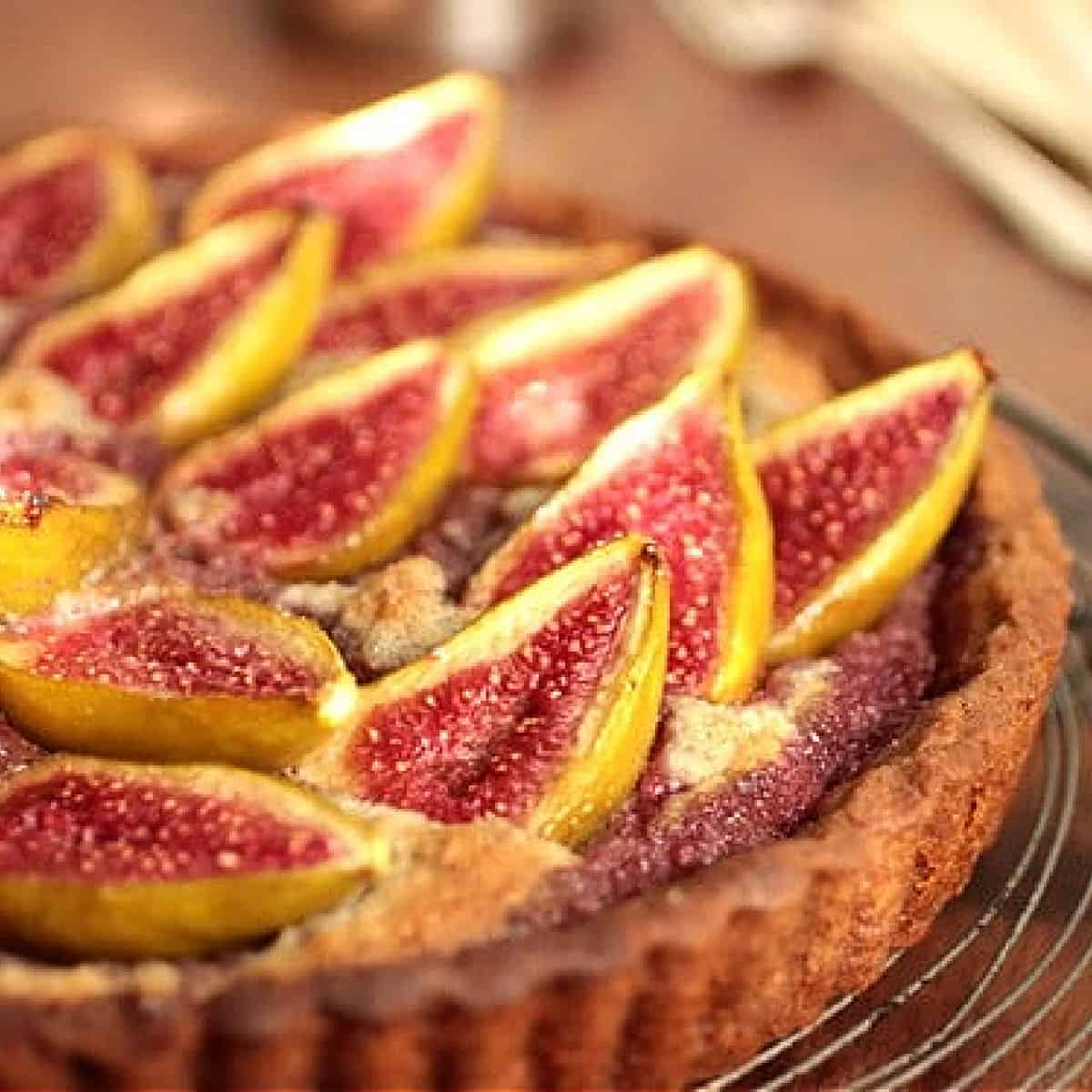 Partial view of fresh fig tart on wooden table.