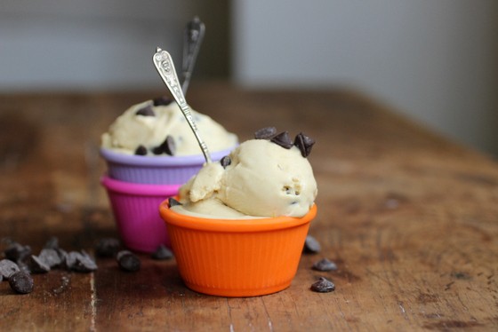 Orange, purple, and pink ramekins with chocolate chip ice cream on a wooden table. 
