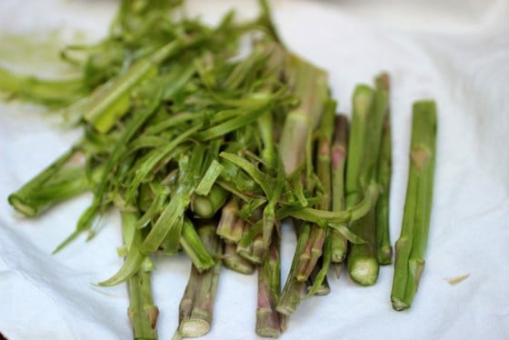 Pile of peeled asparagus with skins on a white paper napkin.