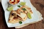 Chicken quesadillas triangles on white plate, wooden table