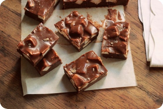 Top view of pieces of chocolate Marshmallow Fudge on white paper on wooden table