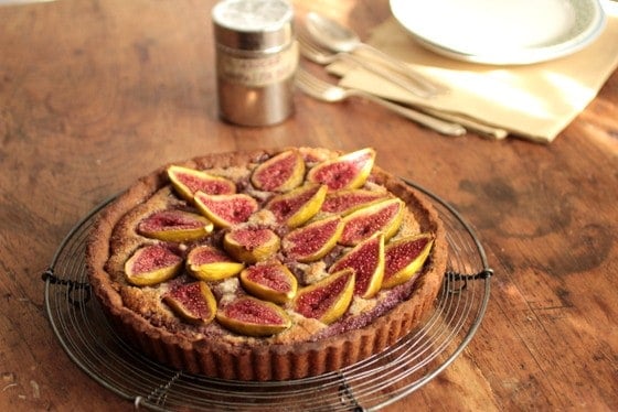 Fresh Fig and Walnut Pie on a wooden table, shaker and cutlery.