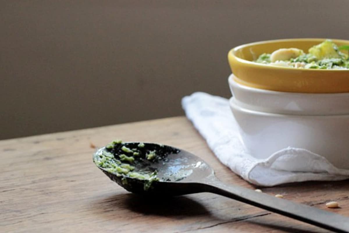 Stacked white and yellow bowls with potato salad on a wooden table. Wooden spoon and kitchen towel. 