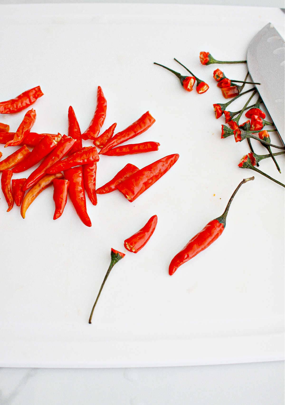 Red, fresh chiles on a white board.