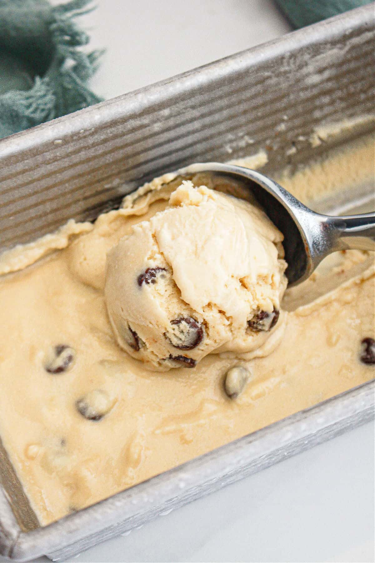 scooping chocolate chip cookie ice cream from a metal pan. 