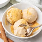 White bowl with cinnamon ice cream balls. Silver spoon.