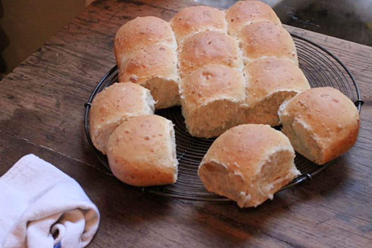 Baked golden buns on a rectangular dark metal pan on a wooden table. 