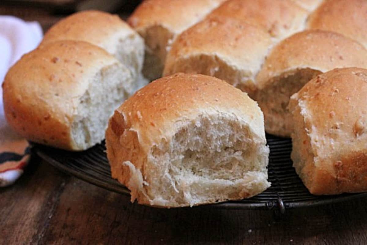 Close up of bread rolls on a dark metal rack. 