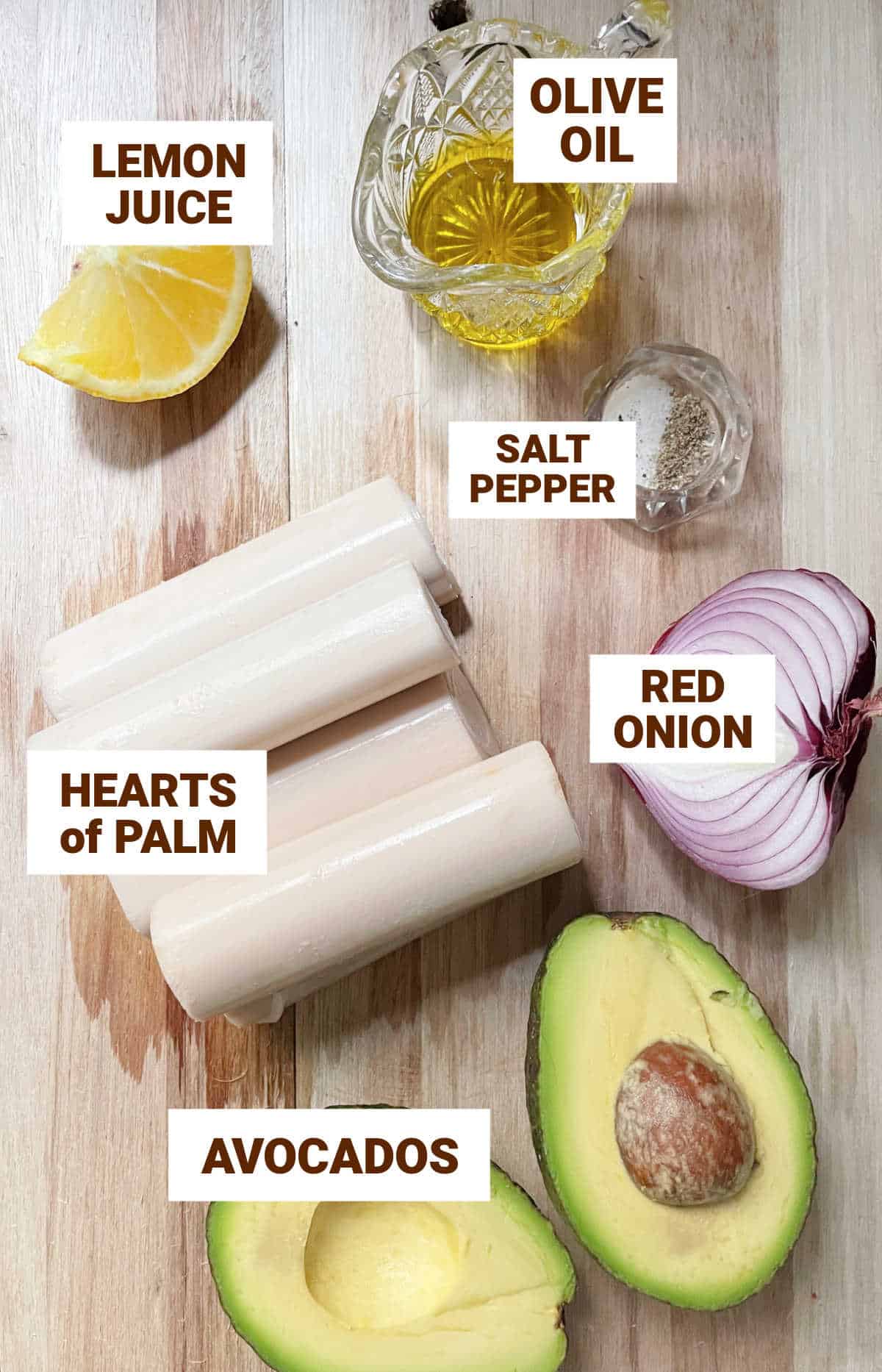 Wooden surface with avocado, hearts of palm, onion, lemon, oil, salt, pepper. Text overlay. 