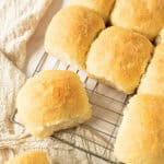 Close-up of wire rack with several coconut buns. Cream-colored cloth.