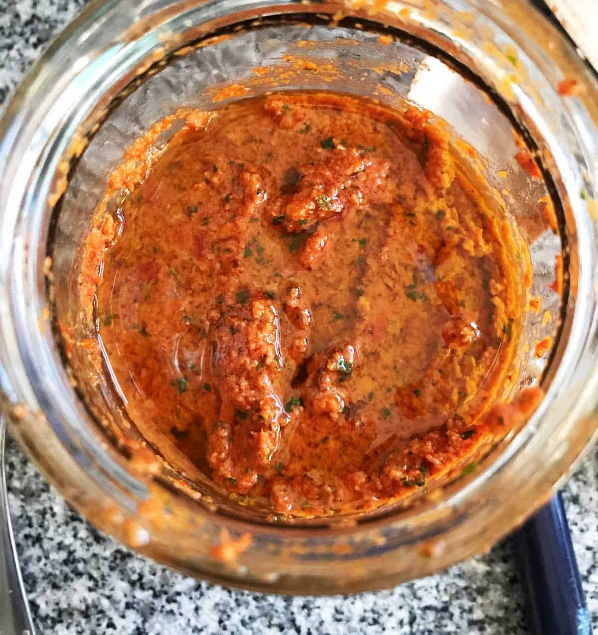 Jar with sun-dried tomato pesto and olive oil. Top view.