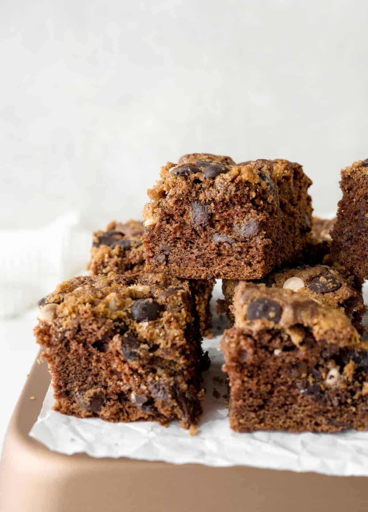 Stack of chocolate crumb coffee cake squares on a copper colored surface with white background.