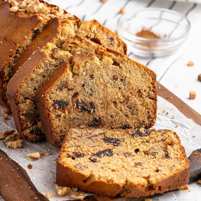 Sliced date walnut loaf on white paper on a wooden board. Striped background.