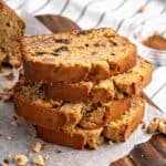 Stacked slices of date nut bread on white paper and a wooden board. Striped background.