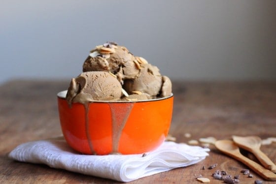 Orange bowl of coffee Ice Cream, wooden table, spoons, white napkin.