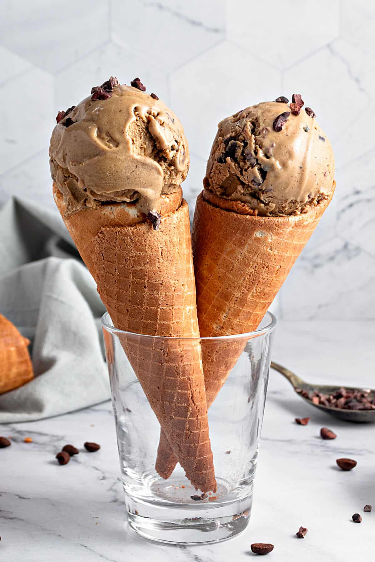 Glass with two coffee ice cream waffle cones. Gray background and surface.