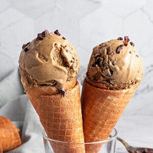 Two waffle cones with coffee ice cream. Gray background.