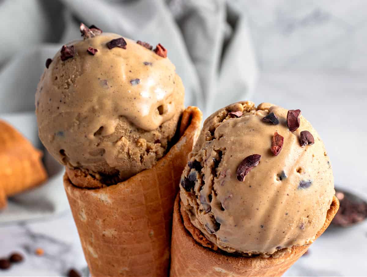 Gray background with coffee ice cream scoops on waffle cones.