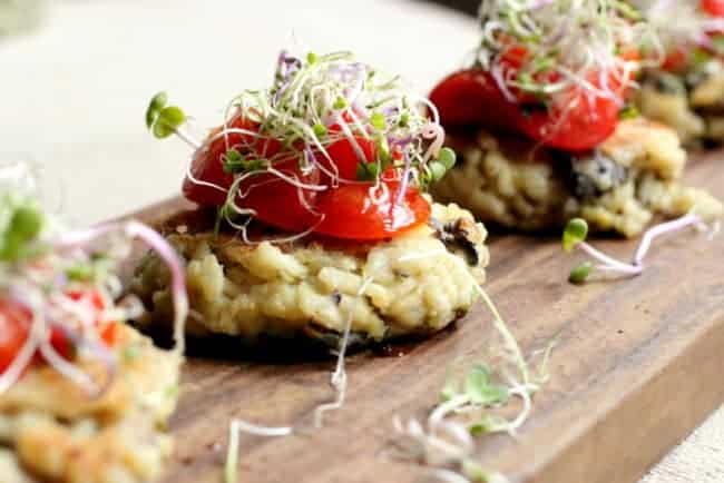 Close up of tomato topped risotto cakes on wooden board