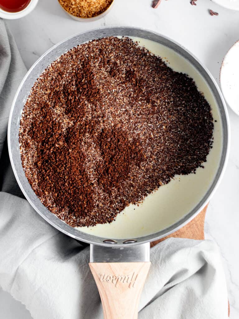 Ground coffee with milk in a saucepan. Top view. Gray background. 