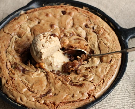 Top view of peanut butter blondies baked in a cast iron skillet with scoop of ice cream and spoon in the center. 