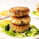 Close up stack of risotto cakes on lettuce leaf. White plate, lemon wedges, white background.