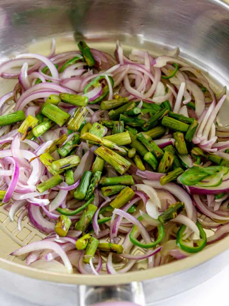 Onion and asparagus in a metal skillet. Close up.