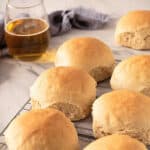 Two rows of dinner rolls on a white marbled surface. Glass of beer and kitchen towel in the background.