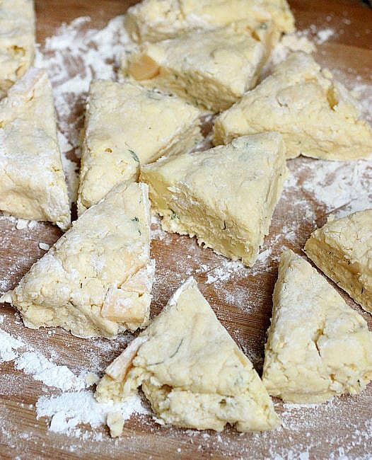 Unbaked Cheese Dill Scone triangles on floured wooden table