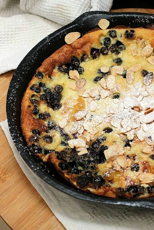 Dutch pancake with berries and almonds baked in a cast iron skillet