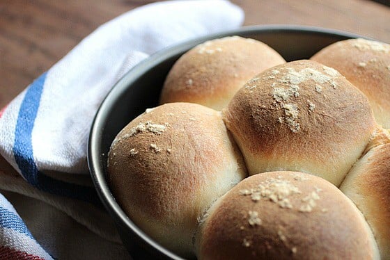 Metal pan with freshly baked rolls on wooden table, kitchen towel
