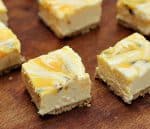 Squares of Passion fruit lemon no-bake cheesecake on wooden table