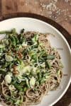sesame soba noodles with green beans on white plate, wooden table