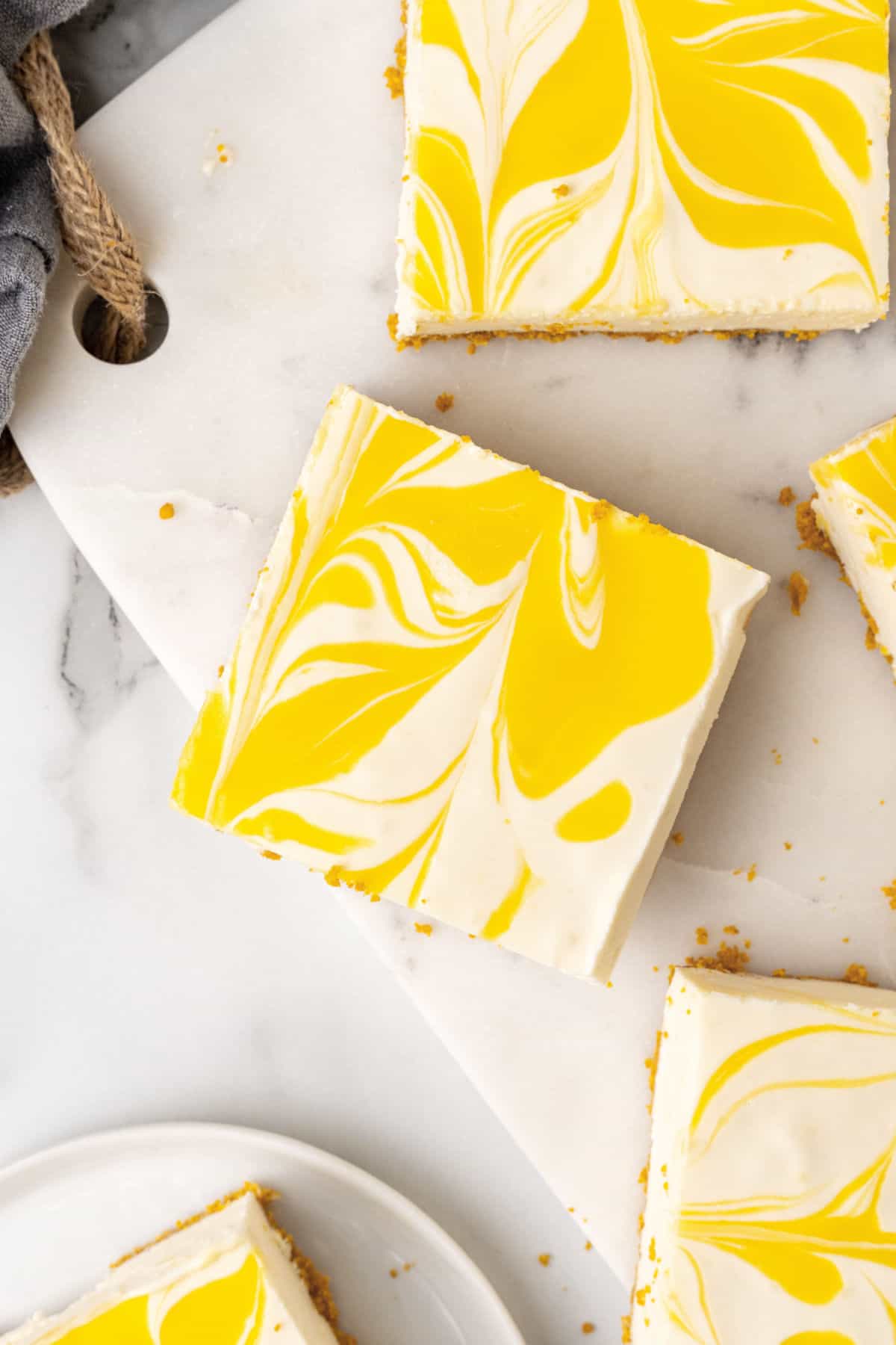 Marbled passionfruit cheesecake squares on a white marble board. 