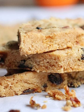 Close up image of three raisin shortbread pieces stacked on white paper.