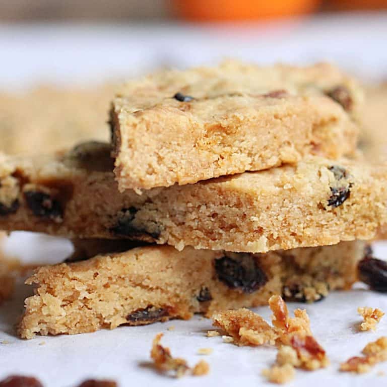 Close up image of three raisin shortbread pieces stacked on white paper.