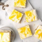 White marble surface with several squares of passion fruit cheesecake. Top view.