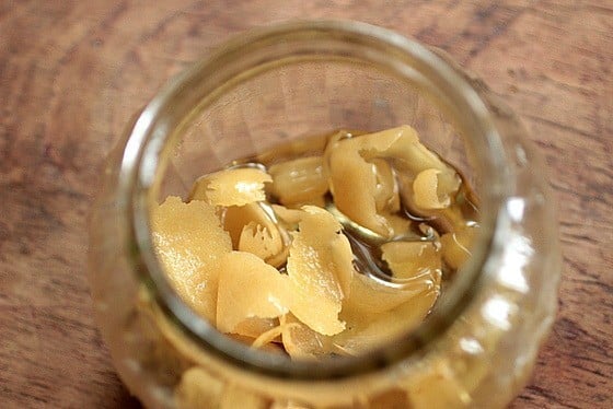 Top view of glass jar with lemon peels in liquid. Wooden surface.