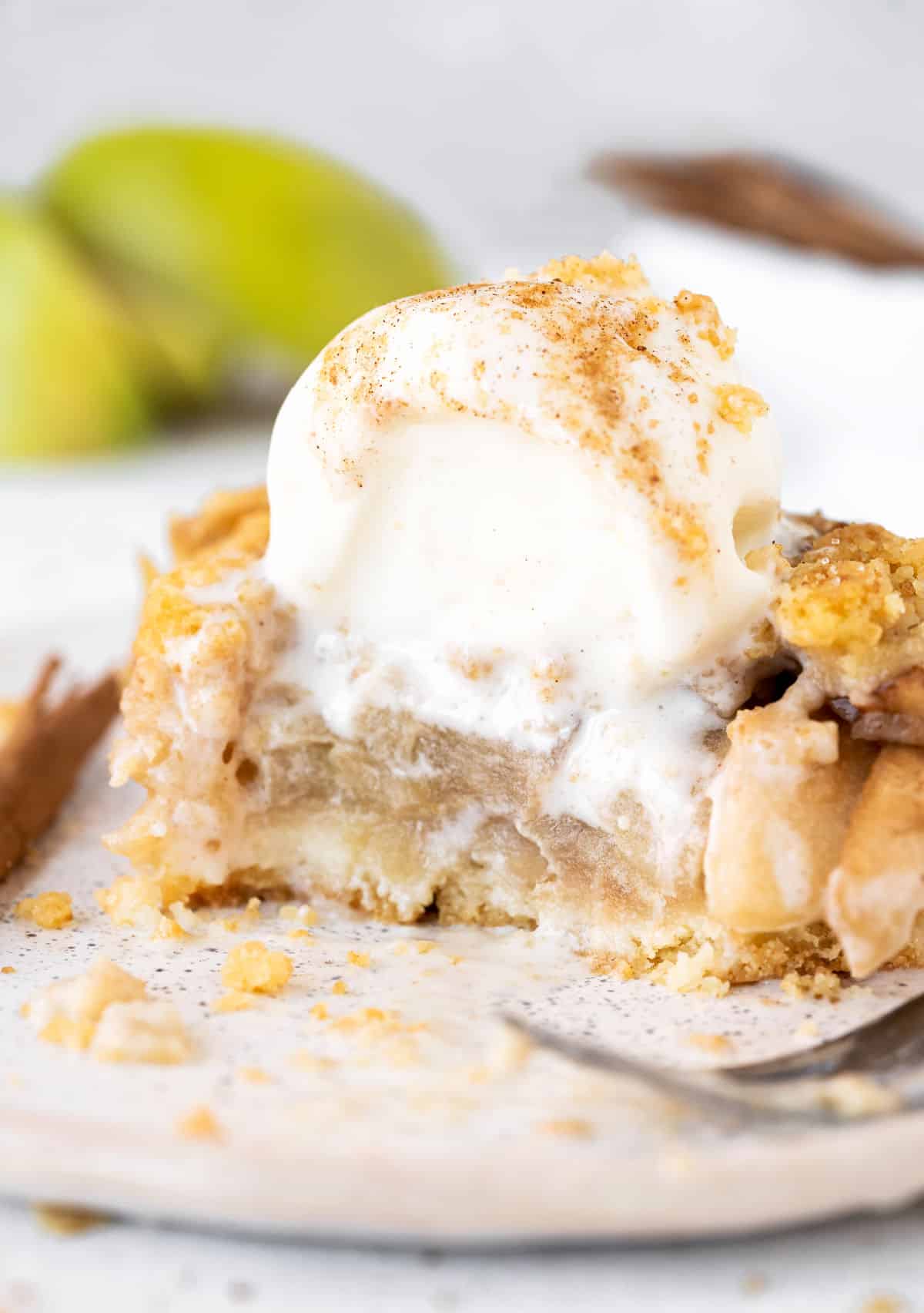 Eaten apple crumb bar on a white plate with scoop of ice cream on top.