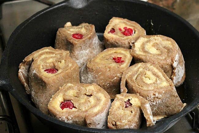 Dark skillet with unbaked raspberry rolls. 