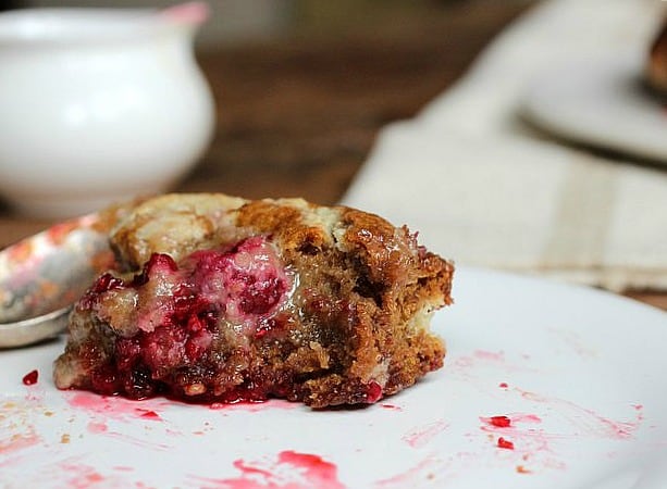 Half a raspberry roll on a white plate. 