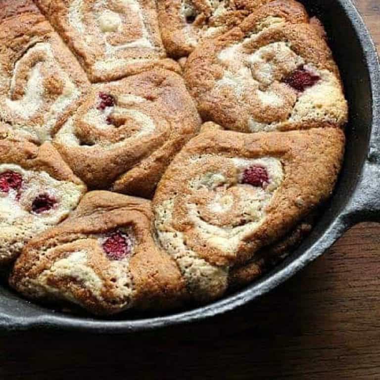 Close up view of cast iron skillet with baked rapsberry rolls.