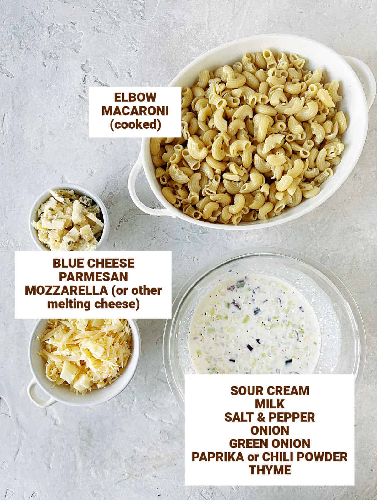 Grey surface with white bowls containing ingredients for blue cheese mac and cheese.