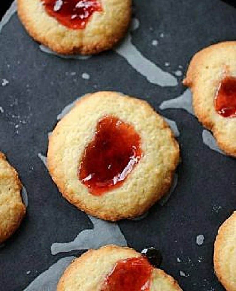Top view of strawberry jam thumbprints on black surface