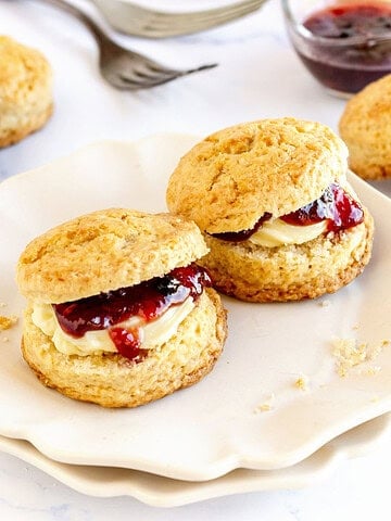 Jam filled scones on a white plate. White background, jam, plain scones.