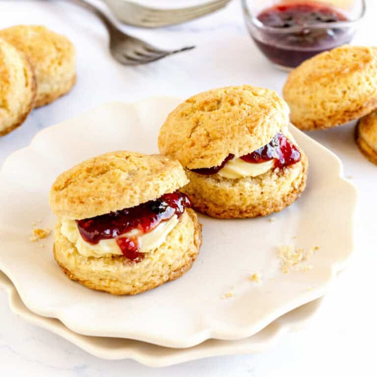 Jam filled scones on a white plate. White background, jam, plain scones.