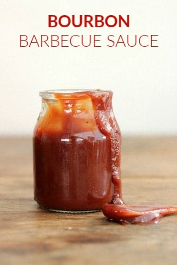 Smeared Jar of barbecue sauce on wooden table, spoon