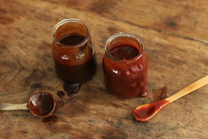 Two jars of Bourbon Barbecue Sauce, spoons on wooden table