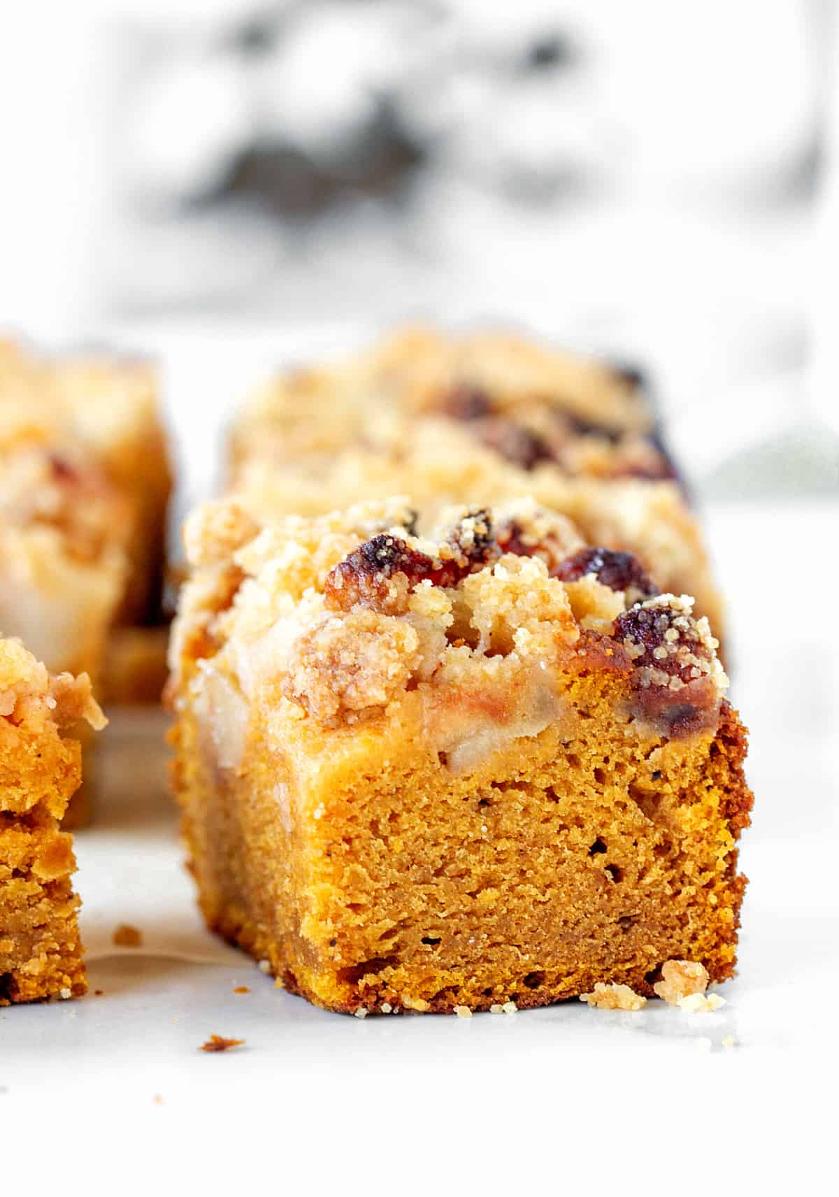 Square of pumpkin cake with apples and crumble, white greyish surface
