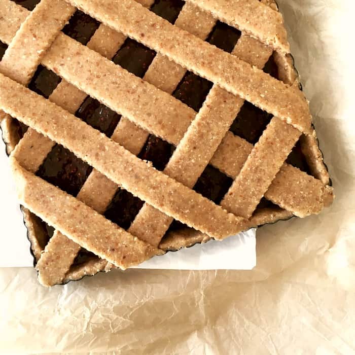 Unbaked lattice square tart on beige parchment paper.